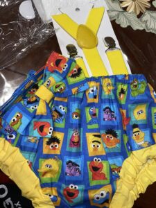 Colorful children's shorts featuring Sesame Street character designs and yellow suspenders.